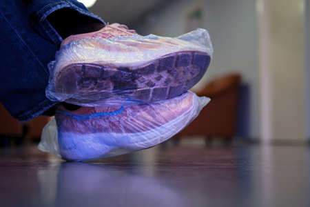 Woman feet in boots with shoe covers from dirt indoorsの写真素材