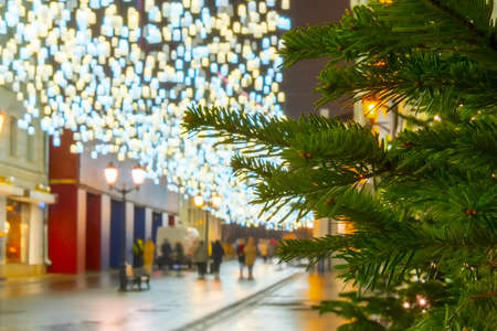 Night city street with people, new year and christmas eve. Christmas tree with garland and lanternの写真素材