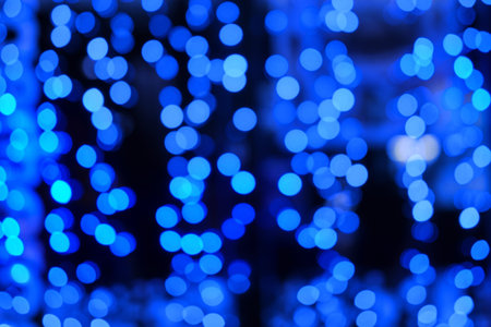 Blurred light background of christmas garlands, blue bokeh of city new year lampsの写真素材