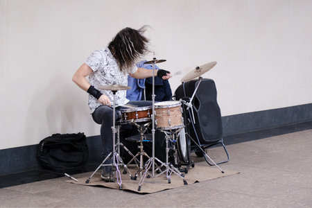 Male musician drummer playing a musical instrument at a public transport stationのeditorial素材