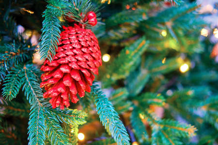 Red cone hanging as decorations on a green Christmas tree, close-upの写真素材