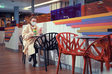 A young woman wearing a medical mask in a new year restaurant. Holidays during the flu virus pandemic, lifestyleの写真素材