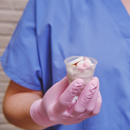 Hand medic in uniform with a handful of pills in a glass, closeupの写真素材