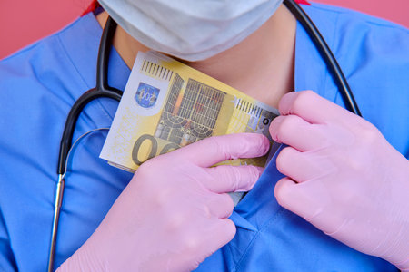 Nurse hides money in a medical uniform, close-up. The doctor in protective gloves covers euro bills for the collar shirtの写真素材