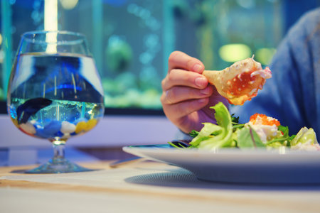 Man holds a crab claw in her hand at a seafood restaurant. Dinner in a cozy fish cafe