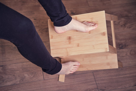An adult woman falls off a stepladder due to a broken chair leg. Problems with labor protection when working at homeの写真素材