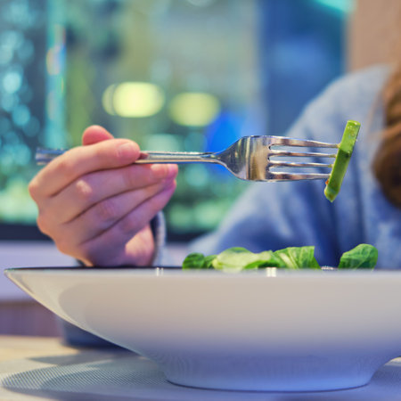 Woman eats a salad with spinach, avocado and squid on blue plate, close up. Dinner at the seafood restaurantの写真素材