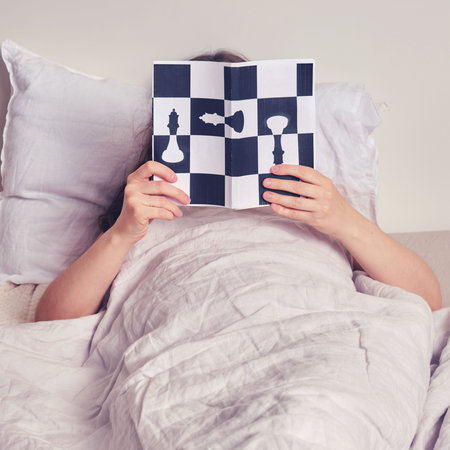 A woman is lying on the bed and reading a chess book. The concept of problems in the life of smart...