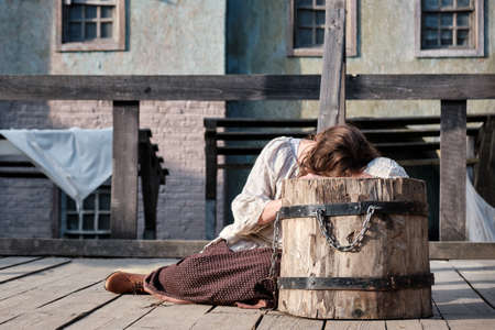 A young woman bows her head over the block at the execution site and criesの写真素材