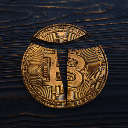 Broken bitcoin coin lies on a dark wooden background, close-upの写真素材