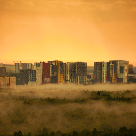 Fog in the autumn forest and the city behind the trees, top viewの写真素材