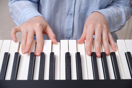The hands of a woman in a blue nightgown on the keys of an electronic piano