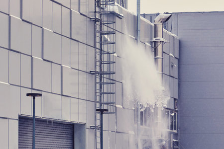 Snow is dumped in winter from the roof of a hangar or warehouseの写真素材