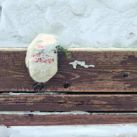 A lost mitten in the snow lies on a bench in a winter parkの写真素材