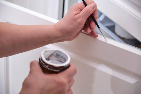 Senior woman with a brush repairs a damaged cabinet door, painting old furnitureの写真素材