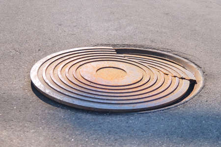 Broken sewer manhole on an asphalt road, damage close-upの写真素材