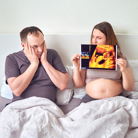 Shocked and excited husband next to pregnant wife and ultrasound resultsの写真素材