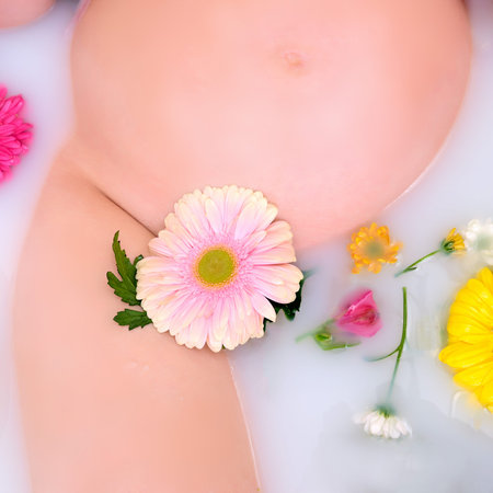 Flowers in a white bath and a pregnant woman belly