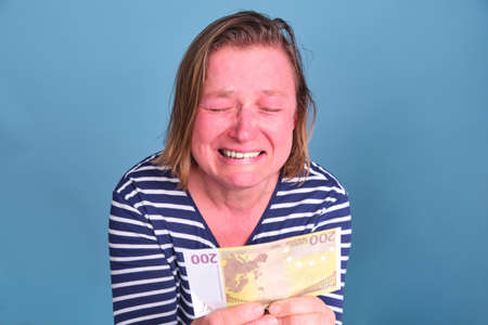 An adult woman cries over a 200 euro bill. Problems with money during the crisisの写真素材