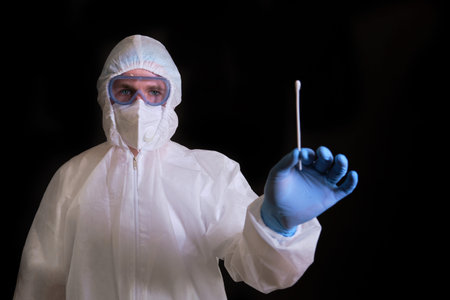 A doctor in a covid protective suit with a sample of a test for analysis for coronavirus