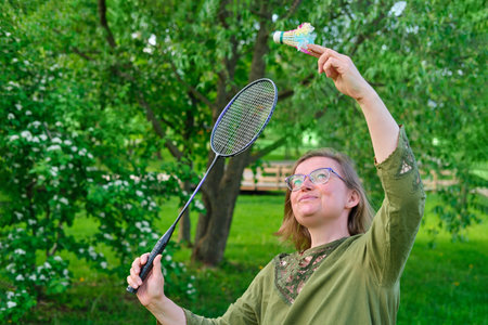 Adult woman playing badminton on the lawn in the park, portraitの写真素材