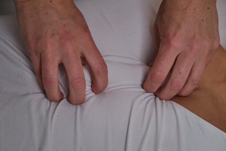 A woman does a holistic back massage on a home bed in the bedroom. Masseuse on the couch massages a...