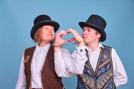 Man and woman with handcuffs and a symbol of love with a heart on a blue backgroundの写真素材