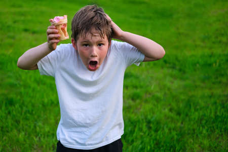 Shocked boy with empty ice cream cup, cheating with foodの写真素材