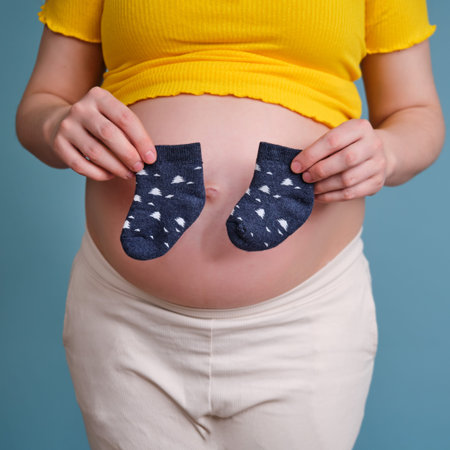 A pregnant woman holds socks for her unborn child in her handの写真素材