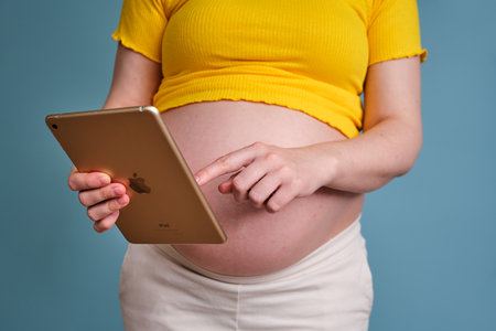 A pregnant woman presses her hand on the screen of an iPad tablet - Moscow, Russia, April 23, 2021のeditorial素材