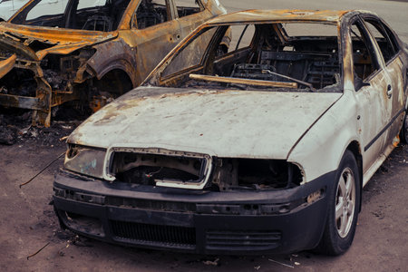 Burnt-out rusty cars on a city street, vandalism. Setting fire to cars by vandals and damage to...