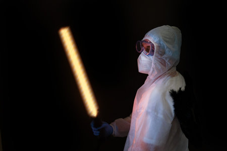 Male doctor with a fiery sword in a protective uniform on a black background