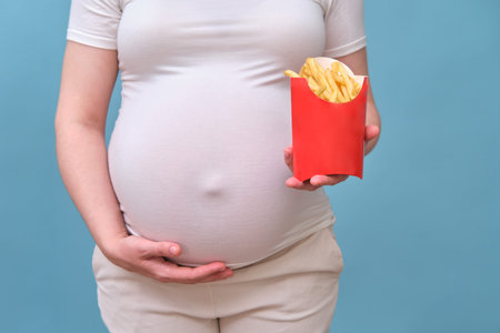 Pregnant woman with French fries on blue background