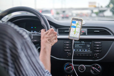A woman drives a car using the navigator in a mobile iphone, yandex maps - Moscow, Russia, June 27, 2021のeditorial素材