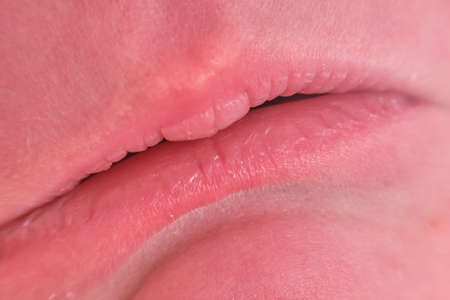 Lips on sad face of a newborn baby, close-up. Macro photo of a healthy child mouthの写真素材