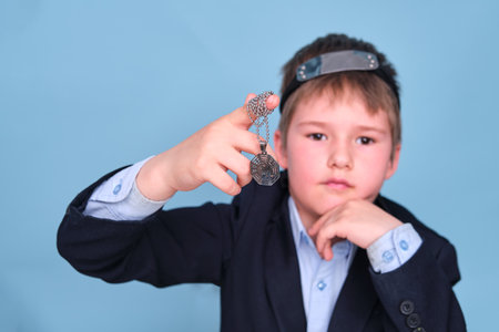 A boy in a school suit with a Buddhist religious symbol, copy space on a blue studio backgroundの写真素材
