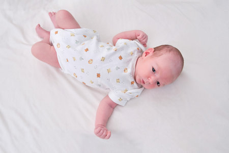 Portrait of a baby boy aged 1 month lying with his eyes open in a crib. Caucasian child in the...