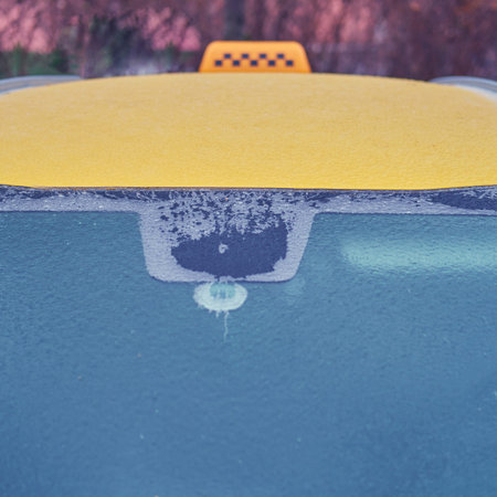 Windshield and roof of yellow taxi car frozen after the first autumn frost