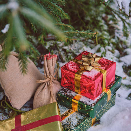 Gifts in red boxes decorated with ribbons are lying under the Christmas tree in the new yearの写真素材