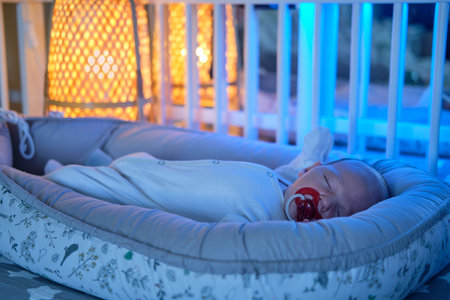 Portrait of a baby boy aged one month sleeping in a crib. Caucasian child in the childrens bedroomの写真素材