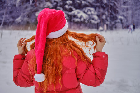 A happy woman stands with a red umbrella in her hands, a winter park with snow-covered treesの写真素材
