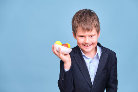 A boy with Easter colored eggs in his hands, copy space on a blue studio background