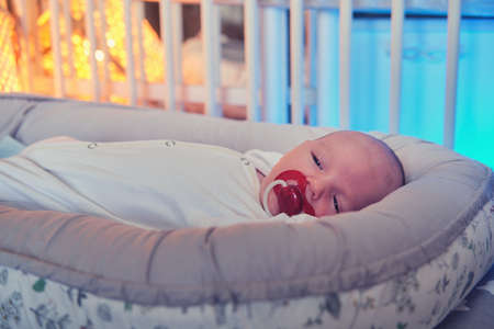 Portrait of a baby boy aged one month asleep in a crib. Caucasian child in the children bedroomの写真素材