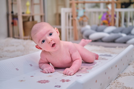 Infant baby boy exercising to keep his head lying on his stomach in the children's roomの写真素材