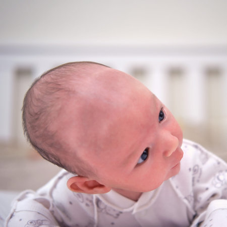 A baby aged 1 month learns to keep his head lying on his stomach. Caucasian boy child in a home...