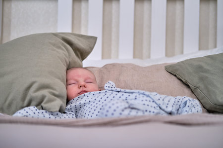 A baby in clothes sleeps on a large bed in the bedroom of adult parents