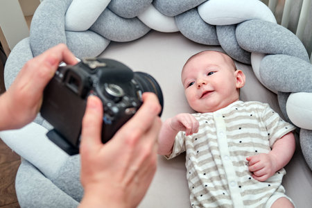 A photographer takes pictures of a newborn baby with a camera on the crib. Photo session of children...