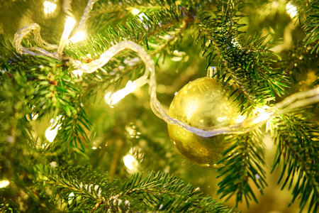 Golden garland as decoration for New Years celebration, close-up. Winter christmas tree with bauble, copy spaceの写真素材