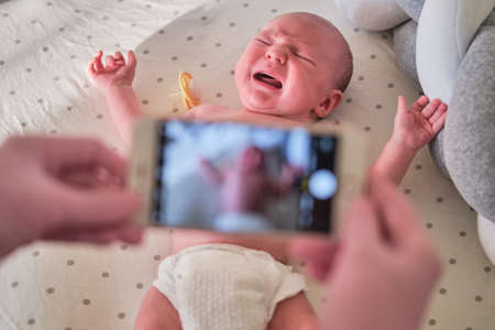 The doctor takes a video on the phone with a newborn baby. A nurse holds an online conference on the treatment of a childの写真素材