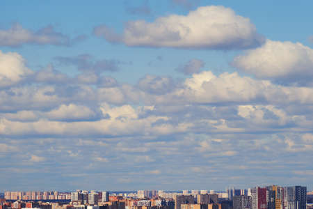 Blue sky background with clouds over the city on a clear sunny dayの写真素材